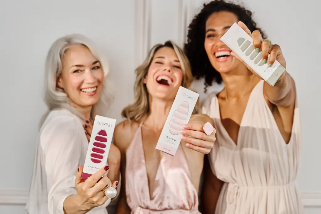 Drei Frauen mit unterschiedlichen Hauttypen halten die MANIKO Nagelprodukte vor die Kamera, Marketingagentur Köln